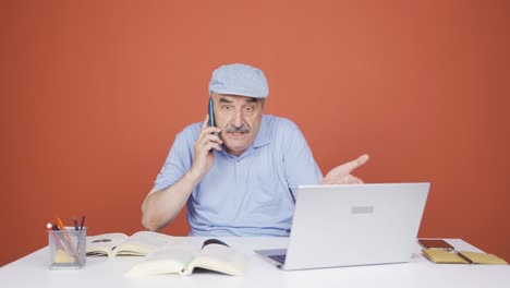 Anciano-Usando-Una-Computadora-Portátil-Hablando-Nerviosamente-Por-Teléfono.